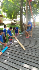 Grupo de alunos pintando os mastros usados nos rituais indígenas